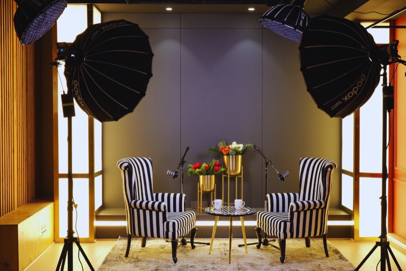 A podcast set with two striped armchairs, microphones on stands and large softbox lights