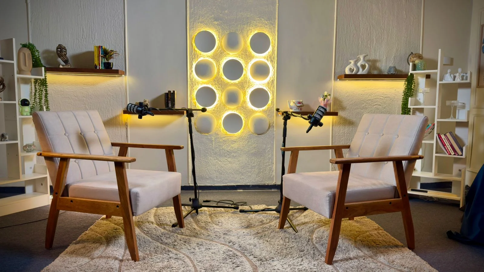 Two armchairs facing each other on a podcast set, each with its own microphone on a stand