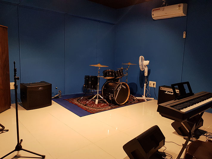 A jam room with a drum kit, guitar amplifiers and a keyboard